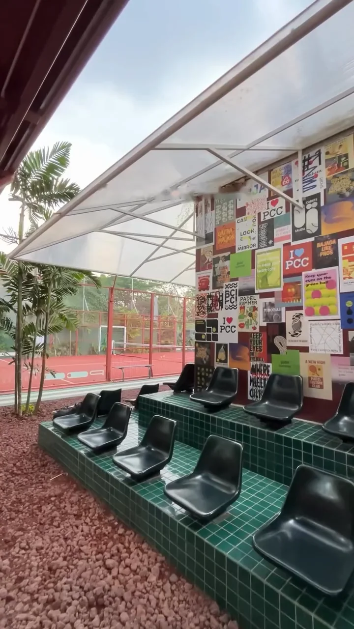 Green-tiled bleachers with black seats in front of a wall of PCC posters