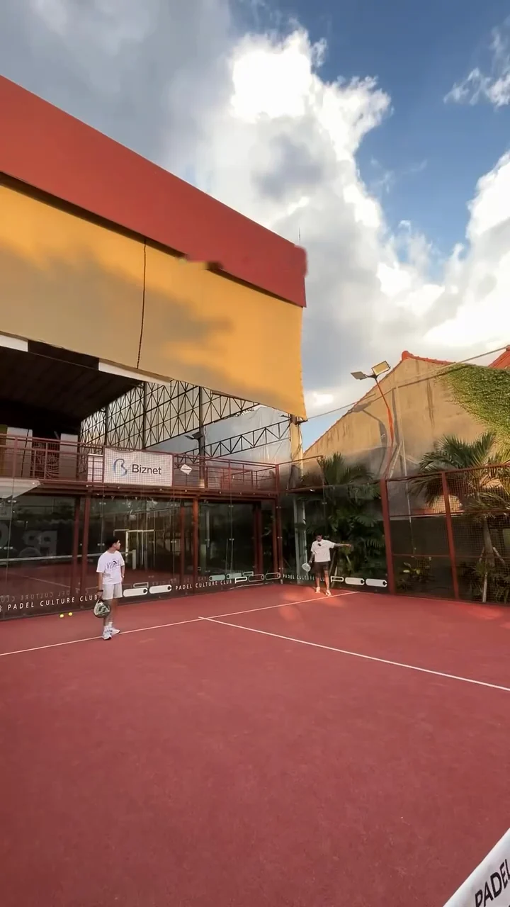 Two players on the terracotta court beside the club's terracotta and yellow roof