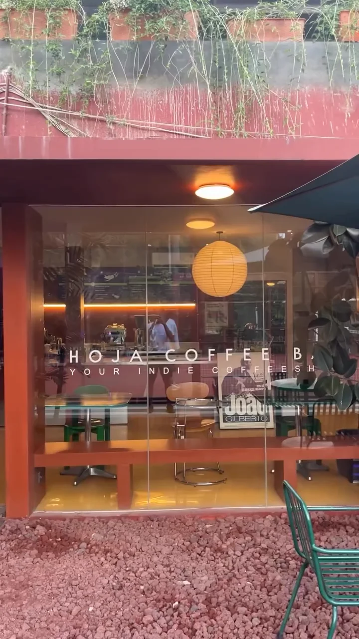 Hoja Coffee Bar behind a glass front, a paper lantern glowing inside