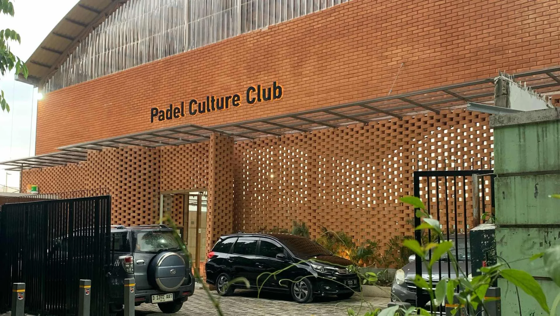 The PCC Bogor clubhouse: a brick and breeze-block façade with 'Padel Culture Club' in steel letters